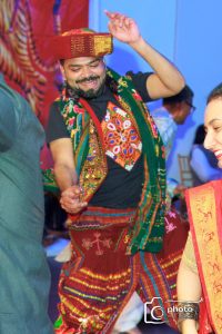 Amid the vibrant festival of Navratri in 2024, a person dances energetically in colorful traditional attire, smiling and savoring the joyous moment. Others around are also dressed in equally vibrant clothing, sharing in the festive spirit.